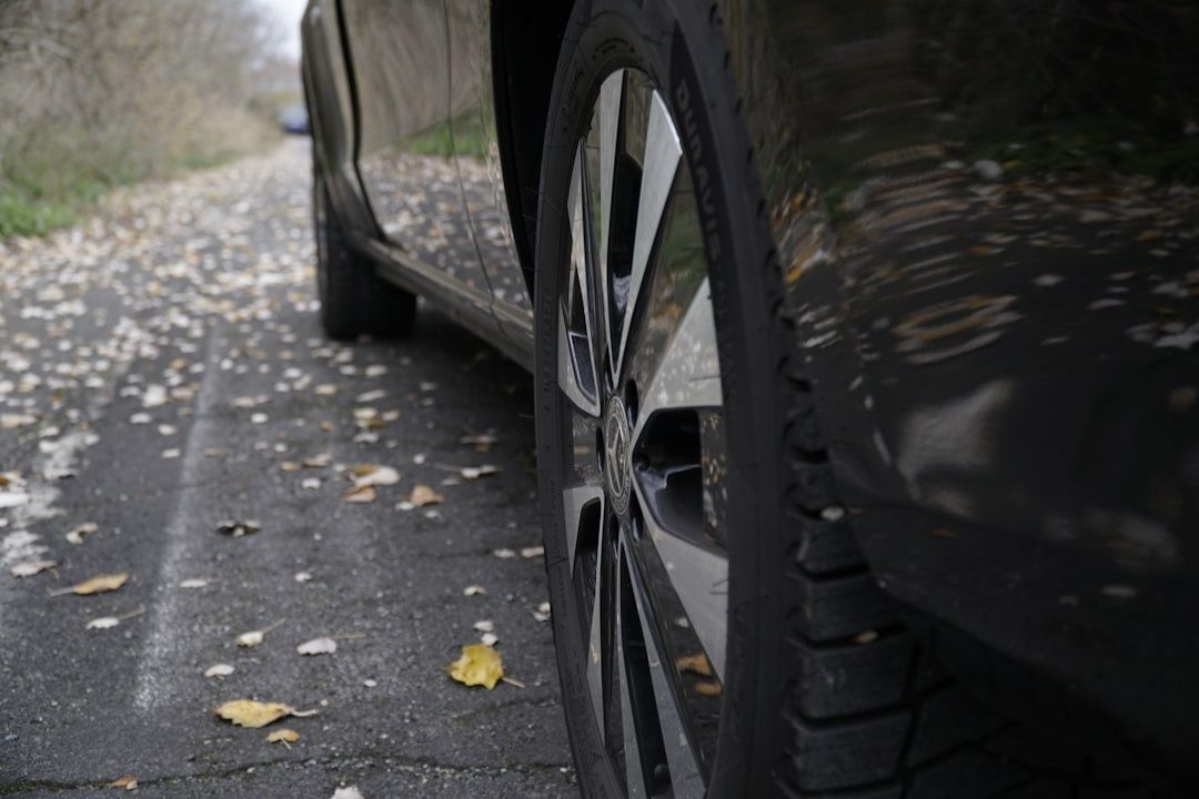 Close-up van een autoband met profiel op een met bladeren bedekte weg