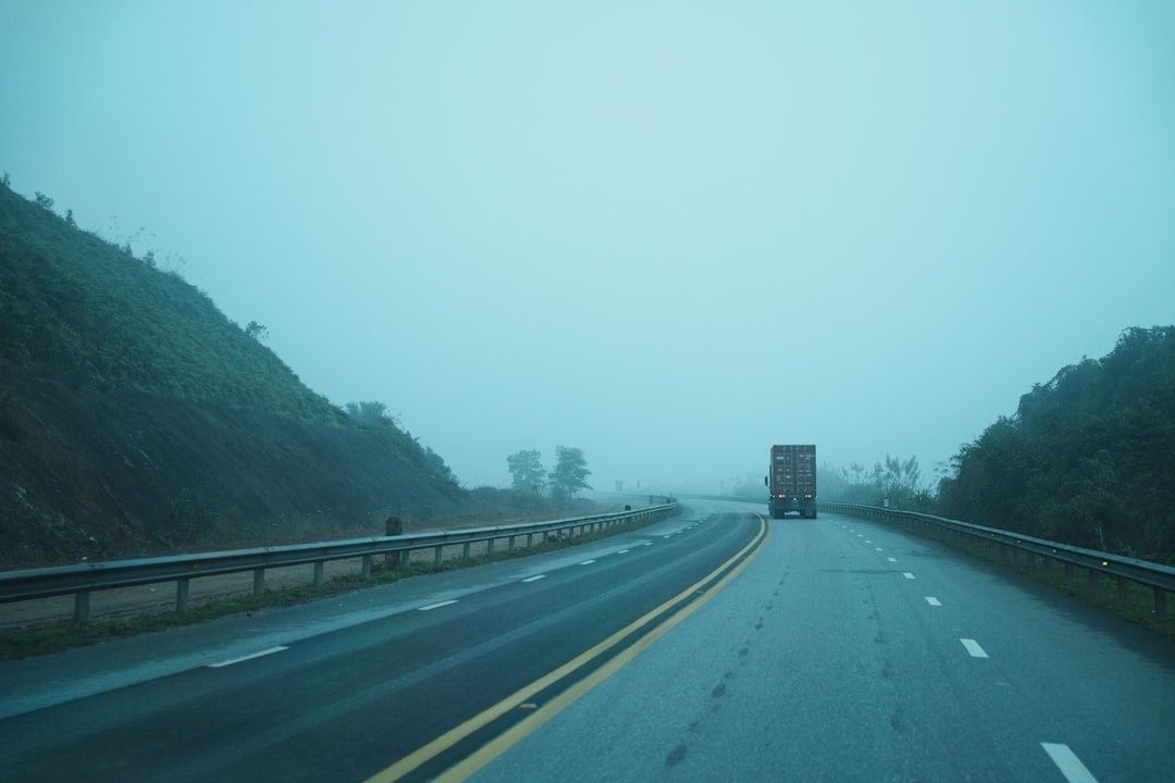 Vrachtwagen rijdt over een natte snelweg in dichte mist