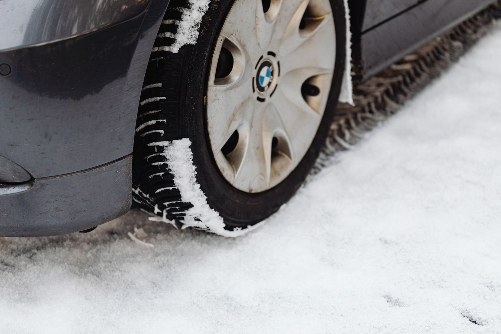 Close-up van een autoband met sneeuw in het profiel op een gladde weg